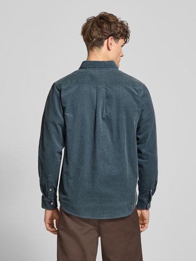 Mężczyznę model nosi Regular Fit Freizeithemd aus Cord mit Button-Down-Kragen od Carhartt Work In Progress, bawełna, model Madison, kolor ciemnoniebieski, struktura sztruksowa, label-stitching, długość tyłu w rozmiarze M: 76 cm, szerokość w rozmiarze M: 44 cm, długość rękawa w rozmiarze M: 64 cm, ujęcie całej sylwetki z tyłu.