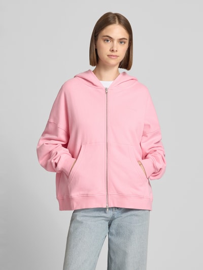 Kobiece modelka nosi Oversized Sweatjacke mit Zweiwege-Reißverschluss Modell 'Flower' von OH APRIL z bawełny, kieszeń kangurka, krój oversized, bluza z kapturem, jasnoróżowy kolor, gładka tekstura, z przodu, ujęcie całej sylwetki