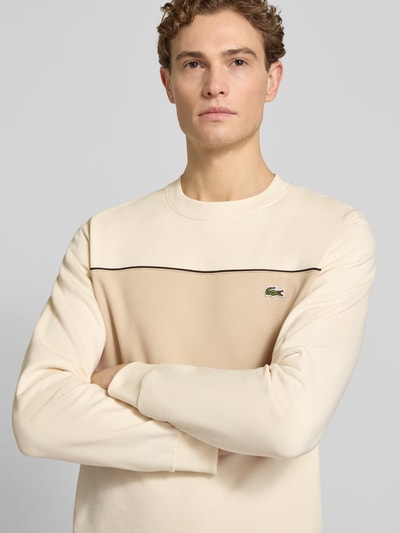Männermodel trägt Regular Fit Sweatshirt aus reiner Baumwolle von Lacoste in Two Tone Beige, Label Patch, Nahaufnahme Oberkörper.