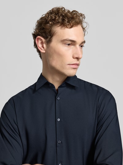 Männermodel trägt Regular Fit Business-Hemd mit Knopfleiste von Jake*s, dunkelblauer Material-Mix mit Stretch-Anteil, Nahaufnahme Oberkörper.