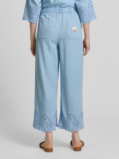 Frauenmodel trägt Hose mit Lochstickerei und französischen Eingrifftaschen von Smith and Soul aus Lyocell in Hellblau, Ganzkörperansicht Rückansicht. Wide-Leg-Fit, elastischer Bund mit Knopf-Reißverschluss, Innenbeinlänge 67 cm bei Größe S.