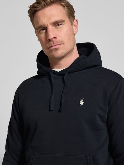 Mannenmodel draagt Relaxed Fit Hoodie uit puur katoen van Polo Ralph Lauren, look effen, logodetail, kangoeroezak, sweat, zwarte kleur, nahaufnahme bovenlichaam.