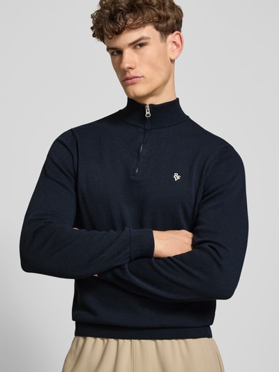 Männermodel trägt Troyer mit Logo-Stitching und kurzem Reißverschluss von REVIEW aus Baumwoll-Mix in Navy, Nahaufnahme Oberkörper. Modern Fit, gerippte Abschlüsse, Rückenlänge bei Größe M 65 cm, Ärmellänge bei Größe M 66 cm.