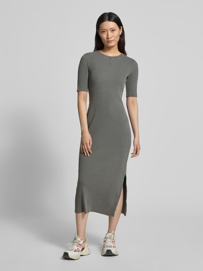 Frauenmodel trägt körpernahes Freizeitkleid aus Baumwoll-Mix Modell 'SEHAARAA' von Armedangels in Used-Look, Rippstruktur, Midi-Länge, Kurzarm, Rundhals, Label Stitching, seitlichem Schlitz, Ganzkörperansicht von vorne.