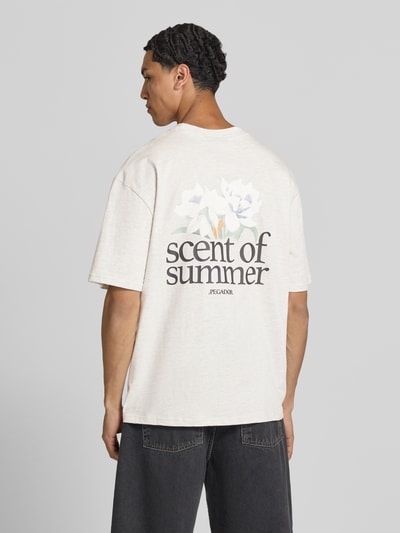 Männermodel draagt oversized heren T-shirt van puur katoen, model 'Miles' van Pegador met labelprint en ronde hals, ruglengte maat M 70 cm. Ganzkörperansicht Rückansicht.