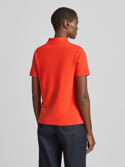 Frauenmodel trägt Poloshirt mit Logo-Stitching und Polokragen von Gant in kräftigem Orange, Reine Baumwolle, Regular-Fit, Rückenlänge 57 cm, Ganzkörperansicht Rückansicht.