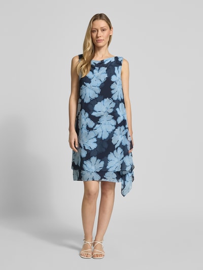 Vrouwenmodel draagt cocktailjurk im allover-look aus fließendem stoff van Christian Berg Cocktail in blauw met bloemmotief, model in a-lijn, chiffon, mini-jurk, cascadehals, ruglengte maat 36: 36 cm, borstwijdte maat 36: 44 cm, geheellichaamsaanzicht van voren.