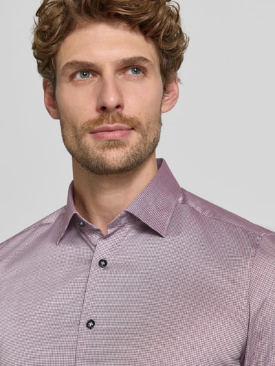 Männermodel trägt Body Fit Businesshemd aus Baumwoll-Mix von OLYMP in feinem Rot-Weiß-Muster, glatte Textur, Nahaufnahme Oberkörper, Herren Businesshemd von OLYMP Level 5.