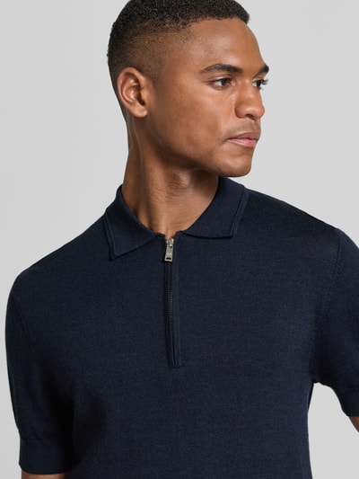Männermodel trägt Slim Fit Poloshirt aus reiner Wolle von Matinique in Dunkelblau, Strick-Optik, Polo-Kragen, Nahaufnahme Oberkörper.