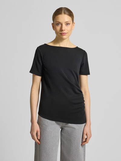 Modelka nosi damski t-shirt z mieszanki materiałów z dodatkiem wiskozy, asymetryczny krój, model 'Helle' od My Essential Wardrobe, okrągły dekolt, drapowania, długość tyłu 60 cm w rozmiarze S, widok całej sylwetki z przodu.
