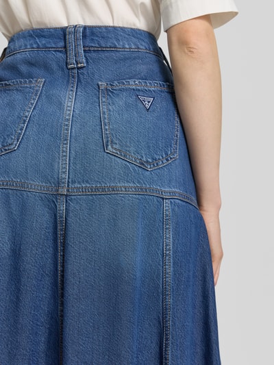 Frauenmodel trägt Maxirock aus Lyocell-Mix in Denim-Optik Modell 'Nidia' von Guess, mittlere Waschung, sichtbare Nähte, Detailaufnahme Rückansicht, 5-Pocket-Design, Baumwoll-Anteil, durchgehende Knopfleiste, leichte A-Linie.