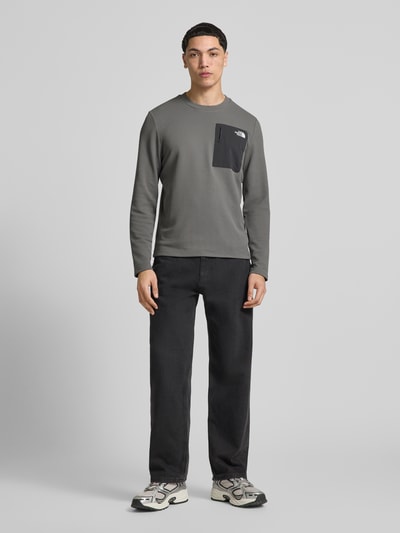 Männermodel trägt Langarmshirt mit Napoleontasche Modell 'KECHA' von The North Face in Grau, Elastischer-Material-Mix, Gerader-Schnitt, Rundhalsausschnitt, Label-Detail, Rückenlänge bei Größe M 67 cm, Ganzkörperansicht von vorne.