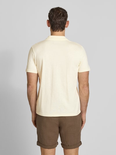 Männermodel trägt Slim Fit Poloshirt mit V-Ausschnitt von MCNEAL aus reiner Baumwolle, cremefarben, braune Shorts, Ganzkörperansicht Rückansicht.
