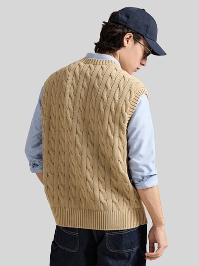 Männermodel trägt Regular Fit Pullunder aus reiner Baumwolle von Polo Ralph Lauren, beżowy, jednolity, sweter, krój regular fit, splot warkoczowy, logo, okrągły dekolt, dzianina, bawełna, Ganzkörperansicht Rückansicht.