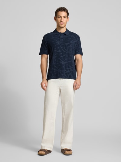 Männermodel trägt Regular Fit Poloshirt aus Baumwoll-Mix Modell 'PE_FLOWER' von BOSS Orange mit Allover-Muster, Ganzkörperansicht von vorne.