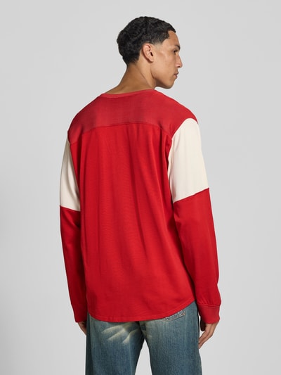 Männermodel trägt Relaxed Fit Longsleeve aus viscosemix van Kenzo, kleur rood met crèmekleurige mouwen, ruggengedeelte, heren shirt met lange mouwen, mix van viscose en katoen, ronde hals, labelstitching, elastische mouwboordjes, ruglengte maat M 73 cm, ganzkörperaanzicht achteraan.