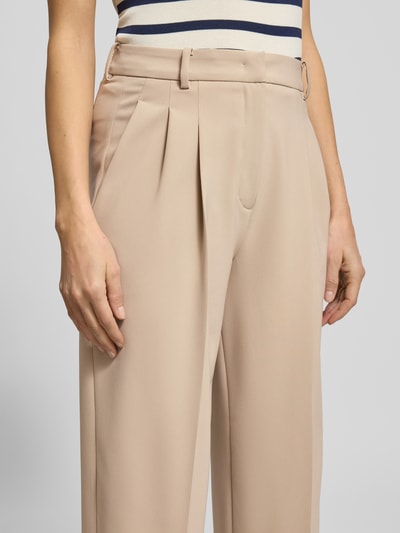 Vrouwenmodel draagt Wide Fit Stoffhose mit Gesäßtaschen Modell 'Emilie' van Cambio in beige, met persvouwen, detailopname taille.