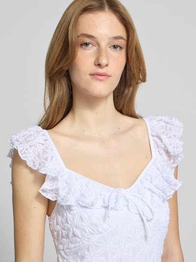 Frauenmodel trägt Midikleid mit Spitze und Schleifen-Detail von Gina Tricot, weißer Material-Mix mit Stretch-Anteil, Nahaufnahme Oberkörper.