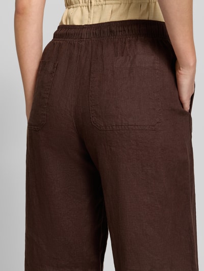 Frauenmodel trägt Damen Leinenhose mit elastischem Bund Modell 'Mileni resort' von OPUS, Gesäßtaschen, braun, Detailaufnahme Rückansicht. Reines Leinen, Wide-Leg-Fit, Bundweite 38 cm, Innenbeinlänge 80 cm bei Größe 36.