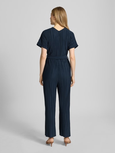 Vrouwenmodel draagt Jumpsuit met plisséplooien en strikriem model 'Pe44arl' van ZABAIONE in donkerblauw met taillering, rugaanzicht.