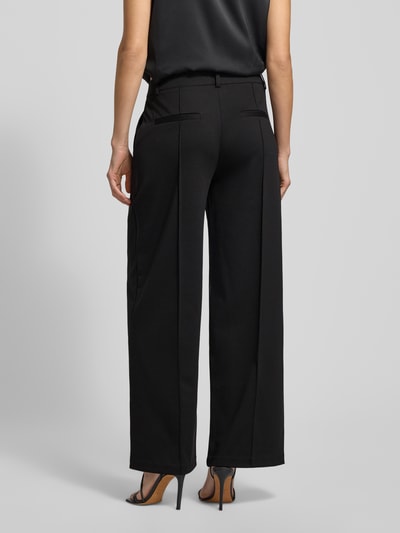 Frauenmodel trägt Wide Leg Stoffhose mit fixierten Bügelfalten Modell 'KATE' von ICHI, Material-Mix mit Viskose-Anteil, Paspeltaschen am Gesäß, Ganzkörperansicht Rückansicht.