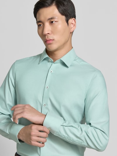 Mannelijk model draagt Slim Fit Business-Hemd aus Baumwolle mit Kentkragen van ETERNA in lichtgroen, puur katoen, knoopsluiting, maat 40: ruglengte 81 cm, schouderbreedte 46 cm, mouwlengte 68 cm, nahaufnahme bovenlichaam.