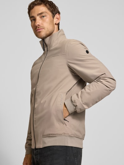 Männermodel trägt Regular Fit Jacke mit Stehkragen Modell 'Alvin' von Didriksons in Beige, glatte Textur, Ganzkörperansicht von vorne.
