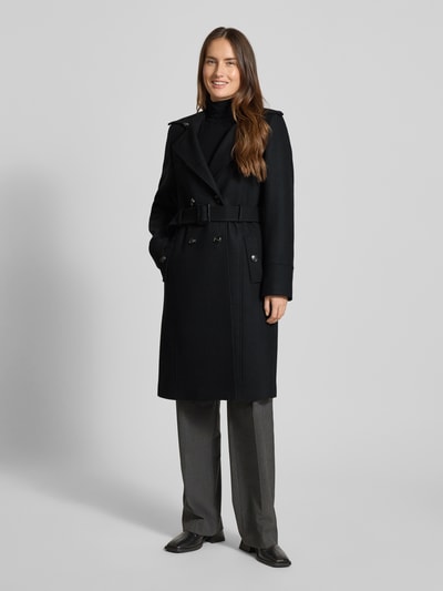 Frauenmodel trägt Mantel aus Woll-Mix mit Gürtel von Jake*s Collection in Schwarz, Slim-Fit, Zweireiher, Umlegekragen, Ganzkörperansicht von vorne. Rückenlänge 100 cm, Schulterbreite 38 cm, Brustweite 33 cm, Ärmellänge 62 cm bei Größe 36.