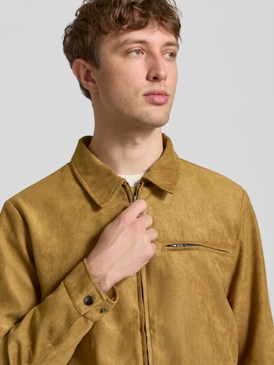 Männermodel trägt Jacke in Leder-Optik Modell 'FOSSY' von Blend in Regular Fit mit Umlegekragen, Reißverschluss, Brusttasche, Nahaufnahme Oberkörper. Rückenlänge 68 cm, Schulterbreite 46 cm, Brustweite 57 cm, Ärmellänge 64 cm bei Größe M. Senfton, glatte Struktur.