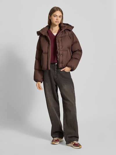 Modelka kobieca nosi Regular Fit Steppjacke mit Kapuze Modell 'Bubble' od Levi's®, brązowa, pikowana, kieszenie z napami, kaptur z tunelem, elastyczne wykończenia, widok całej sylwetki z przodu.