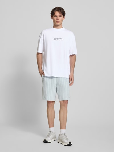 Męski model nosi Oversized T-Shirt mit Label-Print Modell 'Ramon' od PEGADOR z bawełny, okrągły dekolt, długość tyłu 70 cm, Ganzkörperansicht von vorne.