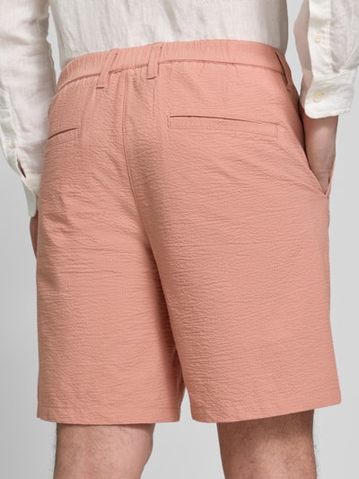 Mężczyzna nosi Regular Fit Bermudas aus Baumwoll-Mix Modell 'KARL' od SELECTED HOMME, różowe, tekstura seersucker, widok z tyłu, zdjęcie całej sylwetki