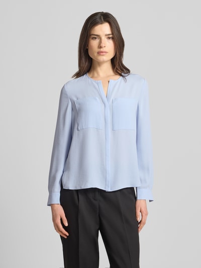 Frauenmodel trägt Regular Fit Bluse mit Brusttaschen von Marc Cain in Hellblau, Tunika-Ausschnitt, langärmelig, Ganzkörperansicht von vorne.