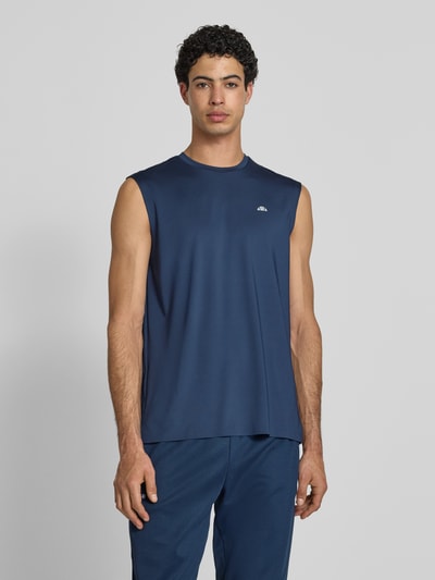 Męski model nosi Relaxed Fit Top mit Logo-Print Modell 'OLIOS' od Ellesse z elastycznej mieszanki materiałów, okrągły dekolt, długość tyłu 74 cm w rozmiarze M, widok całej sylwetki z przodu.
