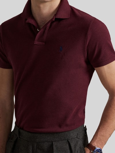 Männermodel trägt Slim Fit Poloshirt aus reiner Baumwolle von Polo Ralph Lauren in Dunkelrot mit feiner Textur, Nahaufnahme Oberkörper.