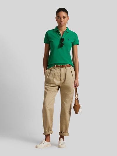 Frauenmodel trägt Slim Fit Poloshirt aus Baumwoll-Mix von Polo Ralph Lauren mit Optik: Unifarben, Logo-Stitching, Polokragen, kurze Knopfleiste, Kurzarm, geschlitztem Rumpfabschluss, Materialverarbeitung: Piqué, Farbe grün, glatte Struktur, Ganzkörperansicht von vorne.