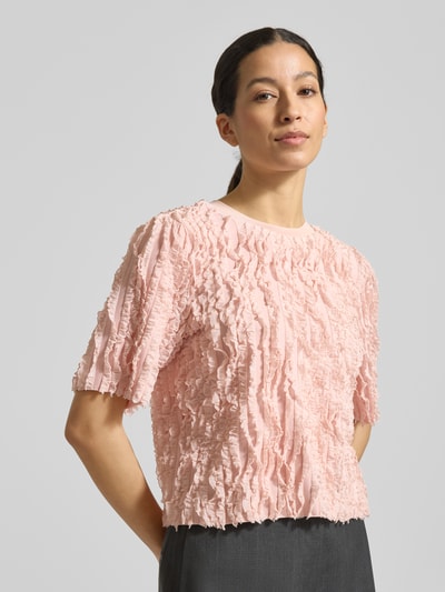 Frauenmodel trägt T-Shirt mit Rüschenbesatz von Jake*s Collection in zartem Rosa, Material-Mix, gerader Schnitt, Nahaufnahme Oberkörper.