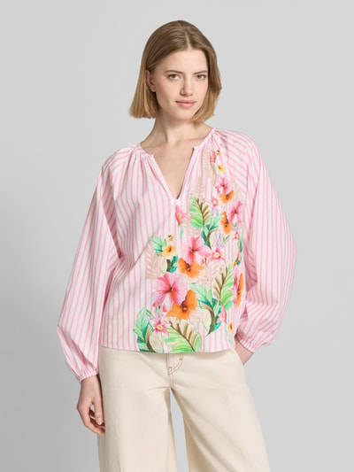 Frauenmodel trägt Bluse mit Tunikakragen und elastischen Ärmelabschlüssen von Emily Van den Bergh, rosa Streifen, Blumenmuster, reine Baumwolle, gerader Schnitt, Ganzkörperansicht von vorne.