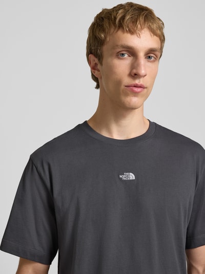 Männermodel trägt T-Shirt mit Logo-Stitching von The North Face aus reiner Baumwolle in Grau, Nahaufnahme Oberkörper.