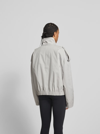 Frauenmodel trägt Jacke mit Stehkragen von black palms aus Baumwolle-Elasthan-Mix in Relaxed-Fit, helle Farbe, Ganzkörperansicht Rückansicht. Seitliche Eingrifftaschen, durchgehender Reißverschluss, Rückenlänge 60 cm, Brustweite 70 cm, Ärmellänge 69 cm bei Größe S.