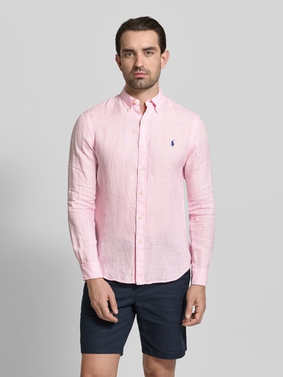 Männermodel trägt Slim Fit Freizeithemd aus reinem Leinen von Polo Ralph Lauren in Unifarben Rosa, Flammgarn-Textur, Ganzkörperansicht von vorne.