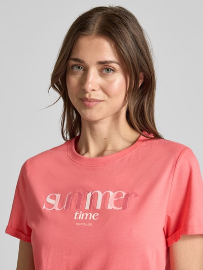 Kobiece model prezentuje Regular Fit T-Shirt aus reiner Baumwolle von Tom Tailor, efekt: jednolity kolor, krój regular fit, aplikacja z nadrukiem z napisem, okrągły dekolt, rękaw: krótki rękaw, wykończenie materiału: dżersej, materiał: bawełna; zbliżenie na górną część ciała