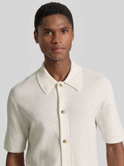 Męskimodel nosi Regular Fit Poloshirt mit Strukturmuster Modell 'ARAAWEN' von Tiger Of Sweden z bawełny, kołnierzyk polo, krótki rękaw, listwa guzikowa, kolor ecru, fakturowany wzór, długość tyłu 68 cm, długość rękawa 28 cm, ujęcie: z przodu, zbliżenie na górę ciała.