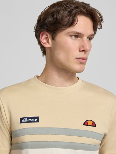 Męski model nosi T-Shirt mit Label-Stitchings und Rundhalsausschnitt od ellesse z bawełny, krój regular fit, kremowy, z logo, Nahaufnahme Oberkörper.