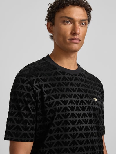 Männermodel trägt T-Shirt mit Label-Stitching von Emporio Armani in Schwarz, Lyocell-Baumwoll-Mix, Regular-Fit, Nahaufnahme Oberkörper.