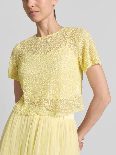 Frauenmodel trägt Cropped T-Shirt mit Pailletten von LACE & BEADS aus Mesh in Gelb, Rundhalsausschnitt, Rückenlänge 41 cm bei Größe S, Nahaufnahme Oberkörper.