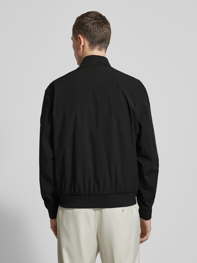 Männermodel trägt Regular Fit Blouson mit Baseball-Kragen Modell 'OSURF' von BOSS Orange, unifarben schwarz, Ganzkörperansicht Rückansicht.