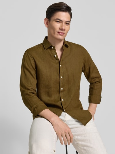 Männermodel trägt Regular Fit Business-Hemd aus Leinen mit Kentkragen von SEIDENSTICKER, olivgrün, glatte Textur, Ganzkörperansicht von vorne. Kontext: Herrenhemd, reines Leinen, Regular Fit, Kentkragen, Knopfleiste, Rückenlänge 79 cm, Schulterbreite 46 cm, Ärmellänge 67 cm.