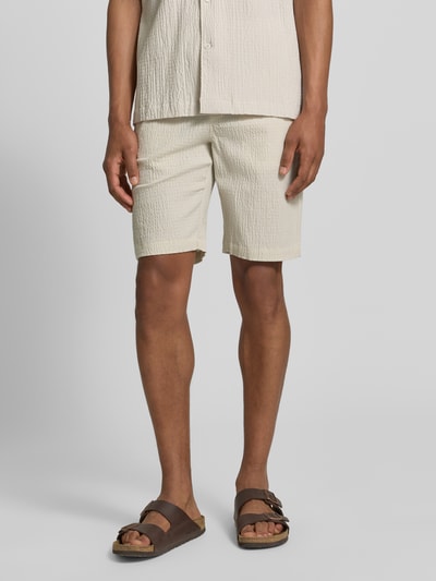 Männermodel trägt Shorts mit elastischem Bund und Strukturmuster von Lindbergh im Baumwoll-Mix mit Stretch-Anteil, Loose-Fit, Eingrifftaschen, Farbe Beige, Bundweite 42 cm, Innenbeinlänge 25 cm, Ganzkörperansicht von vorne.
