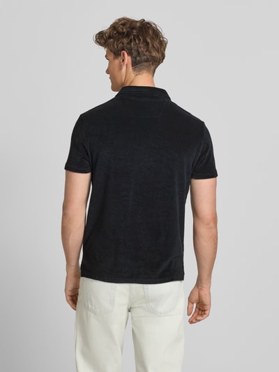 Männermodel trägt Slim Fit Poloshirt aus Frottee von Superdry in Schwarz, reine Baumwolle, kurzärmelig, Rückenansicht Ganzkörperansicht.